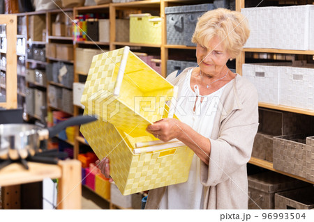 Mature woman buying storage basket Mature woman buying storage basket 96993504