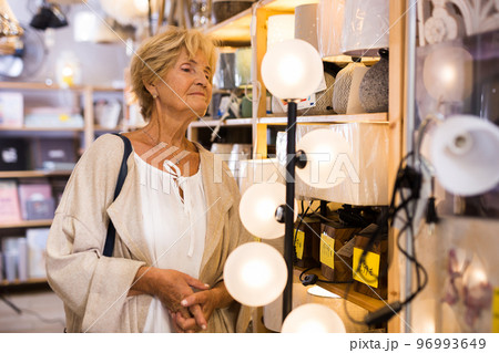 Mature woman choosing new lamp at shop 96993649