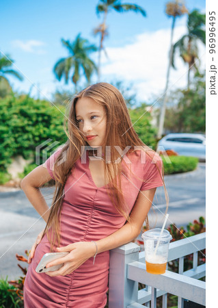 Portrait of adorable teen girl with smartphone and take away drink outdoors 96996495