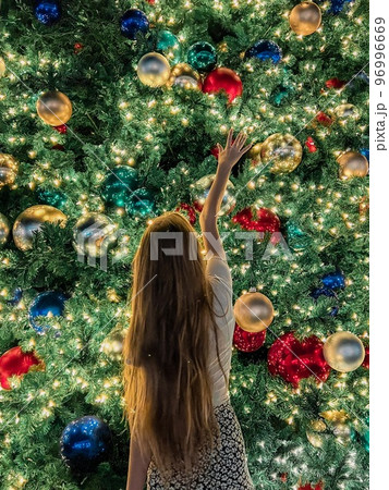 Young girl on the background of the Christmas tree in Miami. Beautiful Christmas Tree at the popular area at Xmas eve and lights 96996669