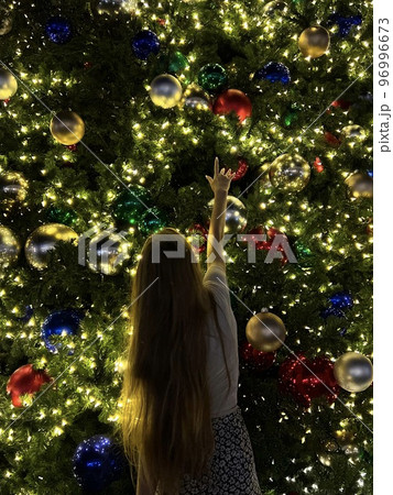 Young girl on the background of the Christmas tree in Miami. Beautiful Christmas Tree at the popular area at Xmas eve and lights 96996673