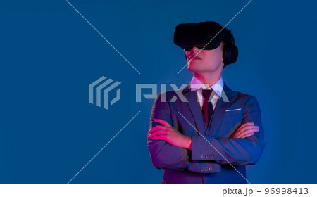 Asian businessman wearing vr headset watching on blue background. Metaverse concept. Asian businessman wearing vr headset watching on blue background. Metaverse concept. 96998413