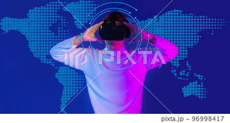 Asian man in white long sleeve t shirt wear vr virtual reality goggles headset posing with hologram blue color background. Asian man in white long sleeve t shirt wear vr virtual reality goggles headset posing with hologram blue color background. 96998417