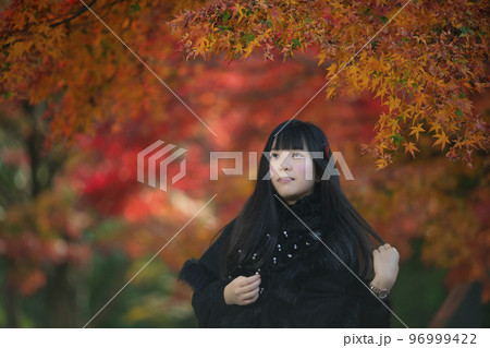 大阪府豊中市の服部緑地の紅葉を背景にしている若い女性 96999422