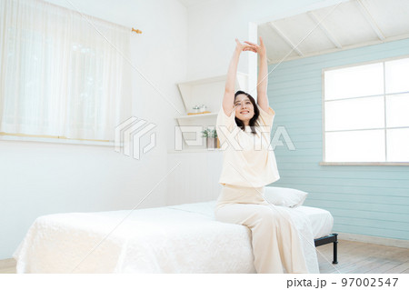 寝室で伸びをする若い女性 97002547