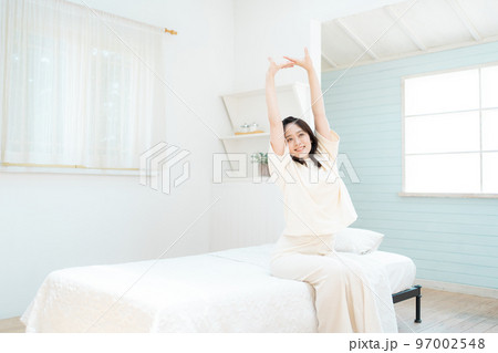 寝室で伸びをする若い女性 97002548