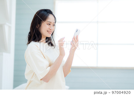 寝室でスマホを操作する若い女性 寝室でスマホを操作する若い女性 97004920