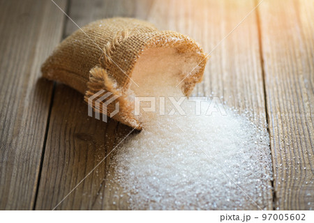Sugar on sack and wooden background, white sugar for food and sweets dessert candy heap of sweet sugar crystalline granulated 97005602