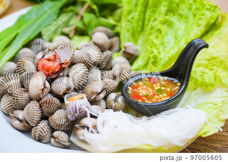 Cockle shellfish seafood plate with fresh vegetable herbs and spices on plate food Cockles background - blood cockle peeled on table with seafood sauce 97005605