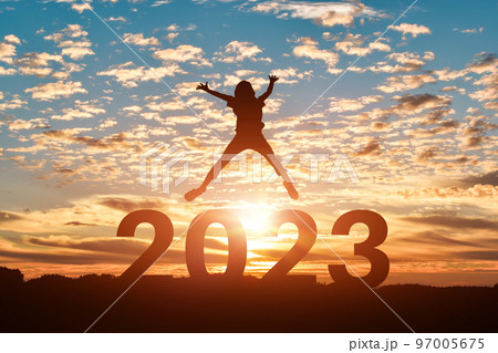 Silhouette of young woman jumping to Happy new year 2023 in sunset or sunrise background. Silhouette of young woman jumping to Happy new year 2023 in sunset or sunrise background. 97005675