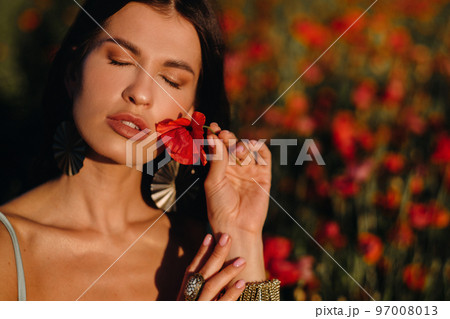 Portrait of a girl in a dress on a poppy field at sunset Portrait of a girl in a dress on a poppy field at sunset 97008013