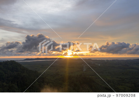 aerial view beautiful yellow sunrise above the mountain in phang Nga valley. slow floating fog blowing cover on the mountain look like as a sea of mist.  scenery golden sunrise at horizon background. 97009208