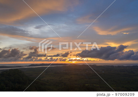 aerial view beautiful yellow sunrise above the mountain in phang Nga valley. slow floating fog blowing cover on the mountain look like as a sea of mist.  scenery golden sunrise at horizon background. 97009209