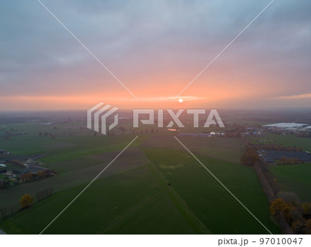 Aerial view of endless lush pastures and farmlands of Belgium under a dramatic colorful sunset sky Aerial view of endless lush pastures and farmlands of Belgium under a dramatic colorful sunset sky 97010047