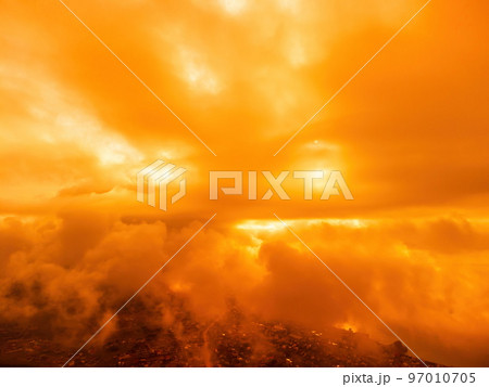 A red burning sunset over the sea with rocky volcanic cliff. Abstract nature summer or spring ocean sea background. Small waves on golden warm water surface with bokeh lights from sun. A red burning sunset over the sea with rocky volcanic cliff. Abstract nature summer or spring ocean sea background. Small waves on golden warm water surface with bokeh lights from sun. 97010705