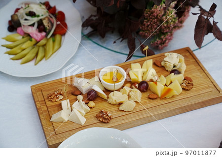 wooden tray with cheese cuts, nuts, grapes and honey.  97011877