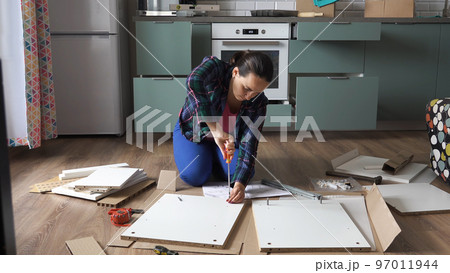 Young woman assembling furniture for her new home, screwing screw Young woman assembling furniture for her new home, screwing screw 97011944