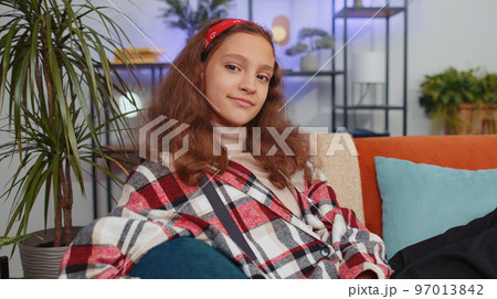 Close-up of happy beautiful preteen student girl child smiling looking at camera at home on couch Close-up of happy beautiful preteen student girl child smiling looking at camera at home on couch 97013842