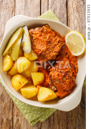 Galinha a africana African chicken Style of Macau served with potatoes, lemon and pickle close up on the pot. Vertical top view Galinha a africana African chicken Style of Macau served with potatoes, lemon and pickle close up on the pot. Vertical top view 97013935