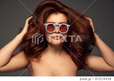 Portrait of young beautiful red-haired woman with perfect hairstyle isolated on dark grey background. Mega hair volume Portrait of young beautiful red-haired woman with perfect hairstyle isolated on dark grey background. Mega hair volume 97014438