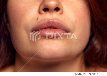 Close-up view of female perfect shape mouth with nude colored lipstick. Moisturizing care. Cosmetological injections. Plump Close-up view of female perfect shape mouth with nude colored lipstick. Moisturizing care. Cosmetological injections. Plump 97014560