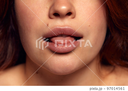 Close-up view of female perfect shape mouth with nude colored lipstick. Moisturizing care. Cosmetological lip fillers 97014561