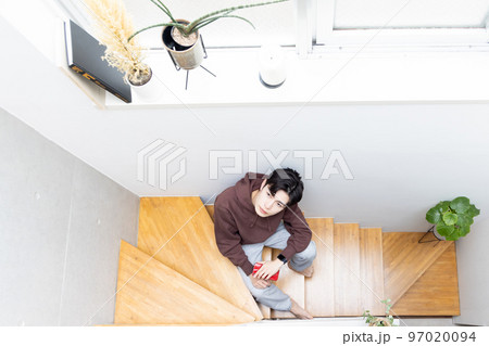 階段に座りスマートフォンを使う男性 97020094