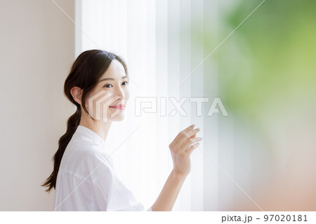カーテンの前に立つ綺麗な女性 97020181