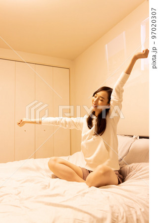 寝室のベッドでストレッチをする女性 97020307