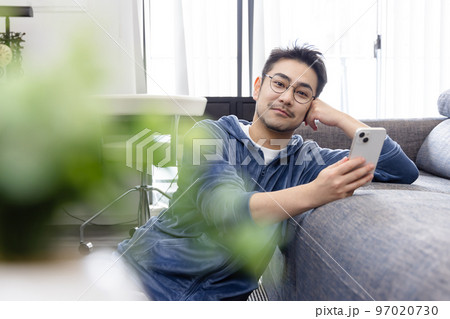 ソファーでスマートフォンを使う男性 97020730