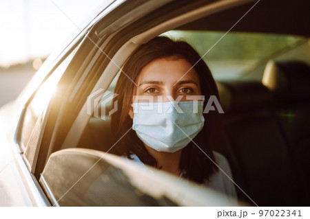 A girl and a boy driving in a car during coronavirus quarantine wearing medical masks. Safe taxi. 97022341