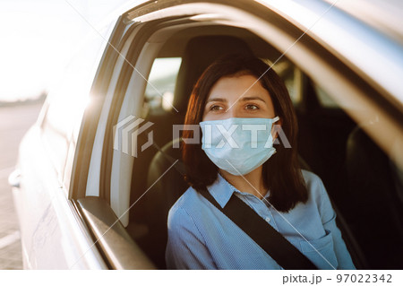 A girl and a boy driving in a car during coronavirus quarantine wearing medical masks. Safe taxi. 97022342