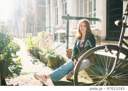 Portrait of a beautiful girl on a sunny day. Streets of Amsterdam. A girl enjoys her lifestyle. 97023283