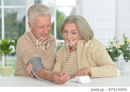 old couple measuring blood pressure together old couple measuring blood pressure together 97024004