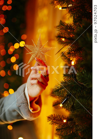 Young woman posing by the christmas tree at winter holidays. Light decorations in the streets. Young woman posing by the christmas tree at winter holidays. Light decorations in the streets. 97024703