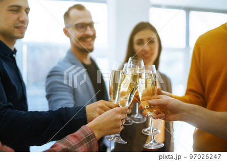 Clinking glasses with champagne. Happy coworkers celebrating their business achievement. 97026247