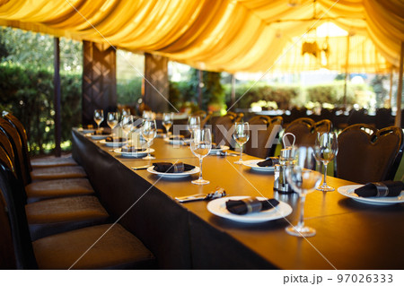 Sparkling glassware stands on long table prepared for wedding dinner. 97026333
