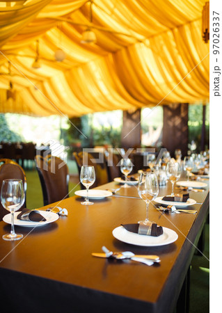 Sparkling glassware stands on long table prepared for wedding dinner. 97026337