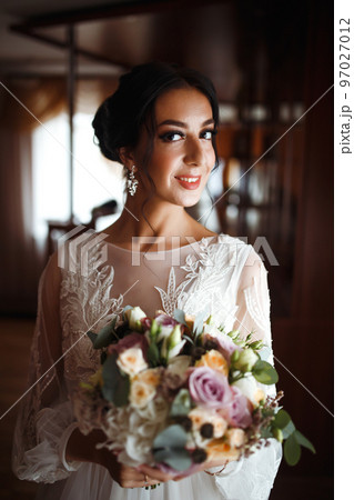 Beautiful bride with a wedding bouquet. Pretty woman with professional make up and hair style. Wedding day. 97027012