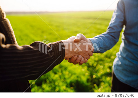 Handshake two farmer on the background of a wheat field at sunset. The concept of the agricultural business. 97027640