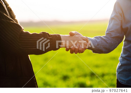 Handshake two farmer on the background of a wheat field at sunset. The concept of the agricultural business. 97027641