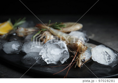 Raw shrimps with ice on grey table, closeup 97028281