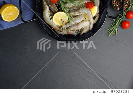Flat lay composition with raw shrimps on black table. Space for text 97028285