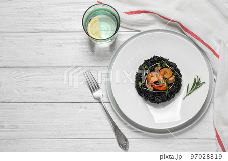Delicious black risotto with seafood served on white wooden table, flat lay. Space for text Delicious black risotto with seafood served on white wooden table, flat lay. Space for text 97028319