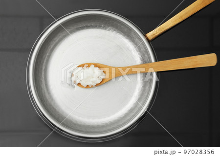 Frying pan with coconut oil and wooden spatula on induction stove, top view. Healthy cooking Frying pan with coconut oil and wooden spatula on induction stove, top view. Healthy cooking 97028356