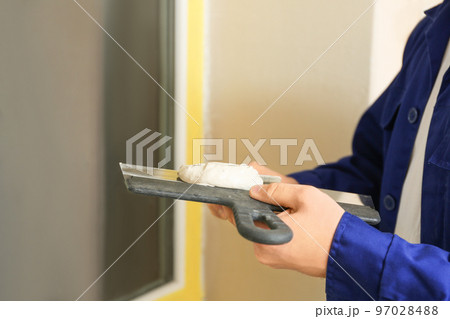 Professional worker with putty knifes and plaster near window indoors, closeup. Interior repair 97028488