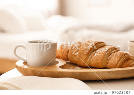 Delicious morning coffee and croissant on table indoors Delicious morning coffee and croissant on table indoors 97028507