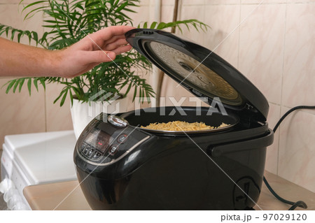 Man closes lid of slow cooker and selects cooking Man closes lid of slow cooker and selects cooking 97029120