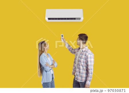 Happy couple use remote to set temperature on air conditioner isolated on yellow background Happy couple use remote to set temperature on air conditioner isolated on yellow background 97030871