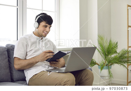 Happy young man using his laptop computer to take online courses of foreign language 97030873